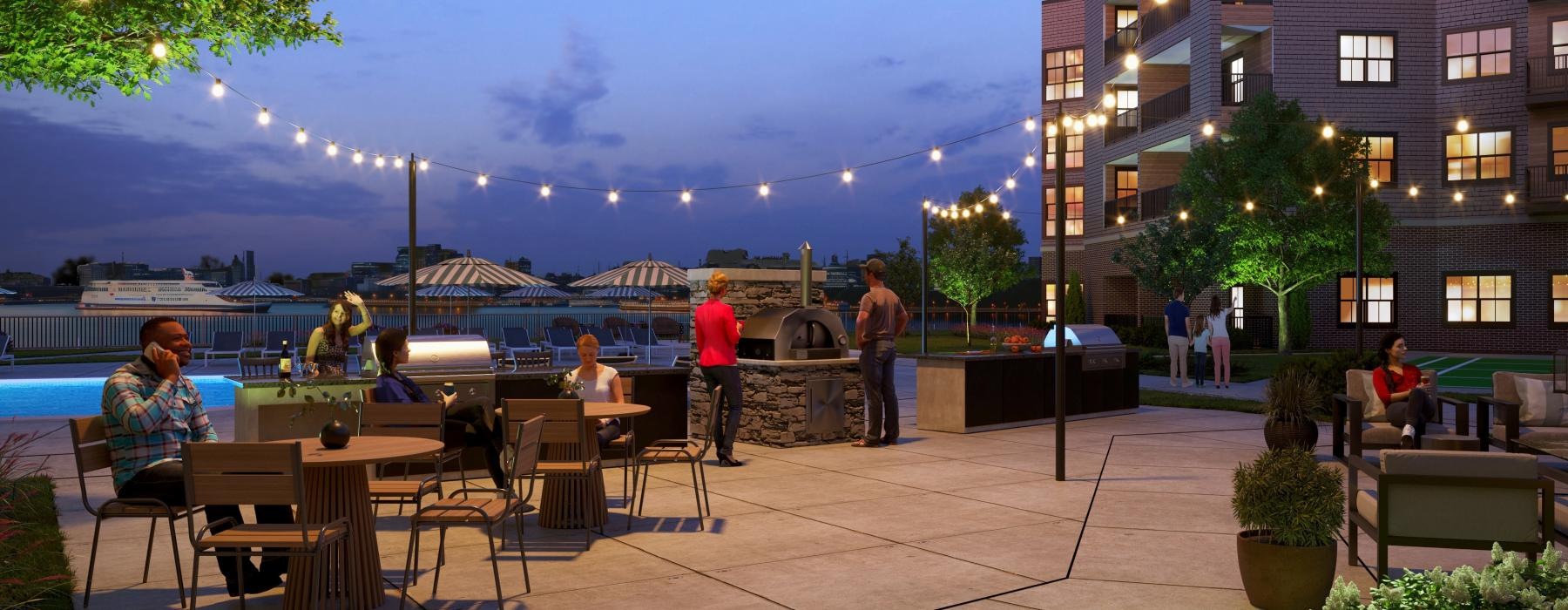 people sitting at tables outside by the community grill at night