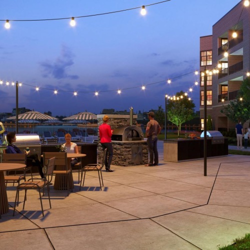 Cutting-edge amenities at your fingertips people sitting at tables outside by the community grill at night